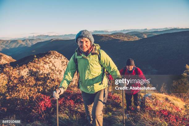 senior couple hiking at autumnal dawn in southern julian alps, europe - hiking pole stock pictures, royalty-free photos & images