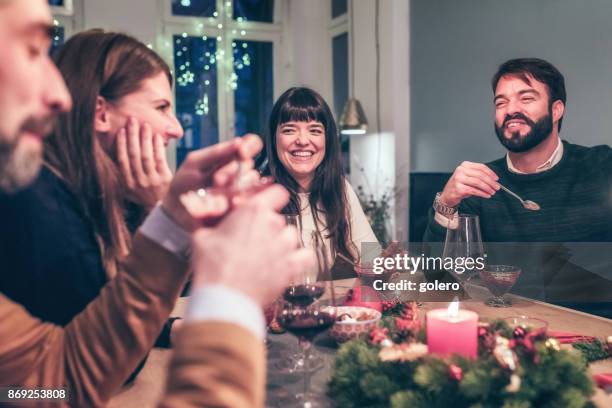 junge glückliche menschen sprechen am weihnachtstisch - familienfeier stock-fotos und bilder
