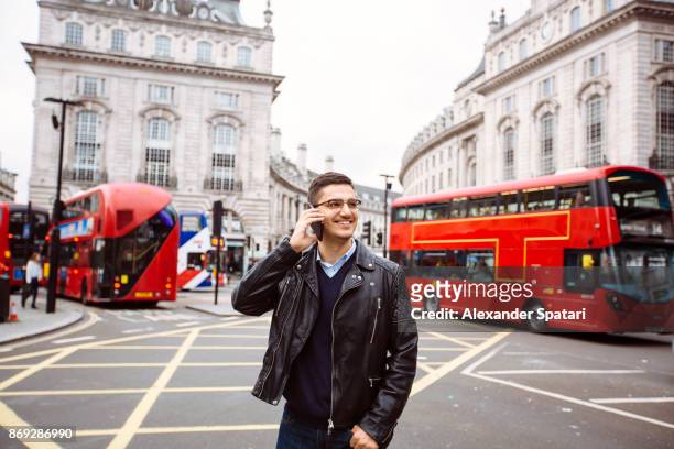 handsome smiling guy talking on the phone on piccadilly circus, london, uk - tourist talking on the phone stock pictures, royalty-free photos & images