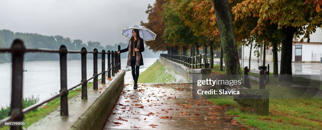 Junge Frau mit Regenschirm im Herbst Regen zu Fuß