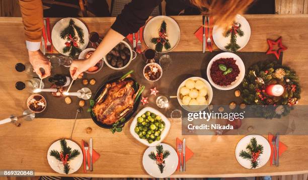 draufsicht der freunde bereiten tisch für weihnachtsfeier - christmas dinner stock-fotos und bilder