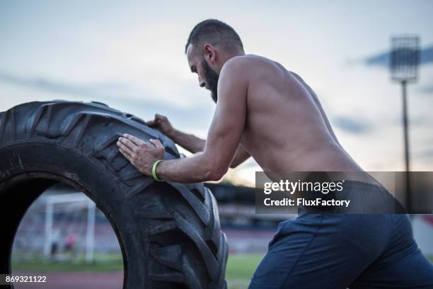 uomo che spinge pneumatico - strongman foto e immagini stock