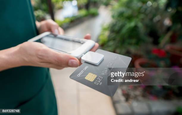 close up van onherkenbaar verkoopster doen de checkout via een credit card reader en smartphone - card reader stockfoto's en -beelden