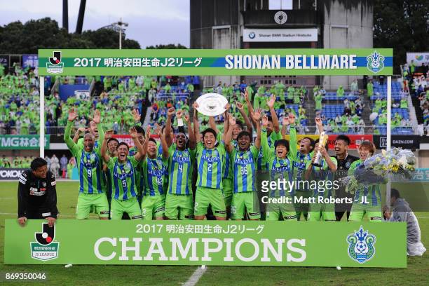 Shunsuke Kikuchi of Shonan Bellmare lifts the trophy as they celebrate the J2 Champions and promotion to the J1 after the J.League J2 match between...