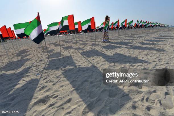 Girl poses next to UAE flags on the eve of the Flag Day at Kite Beach in Dubai on November 2, 2017. / AFP PHOTO / GIUSEPPE CACACE