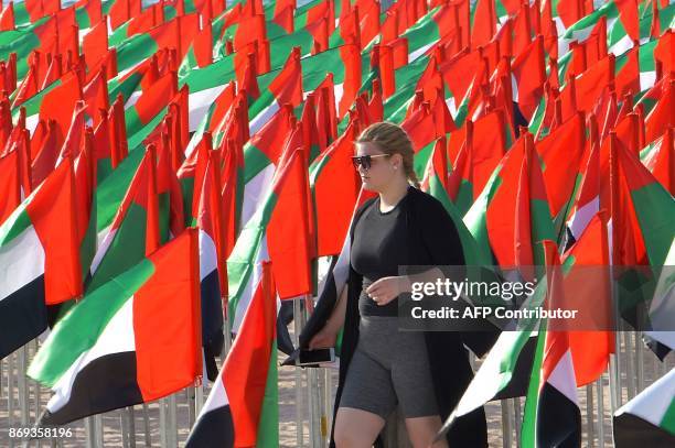 Woman walks in between UAE flags on the eve of the Flag Day at Kite Beach in Dubai on November 2, 2017. / AFP PHOTO / GIUSEPPE CACACE