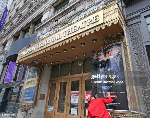 Steven Ehrenberg, top, and Justin Bolla install "Moulin Rouge" artwork in a light box outside the Colonial Theatre in Boston on Nov. 1, 2017. The...