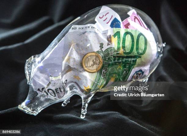 Symbol photo on the subject money save. The picture shows euro banknotes and a one euro coin in a glass piggy bank.