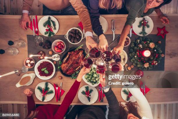 menschen klirren wein gläser am weihnachtstisch - friends toasting above table stock-fotos und bilder