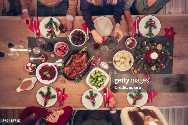 leute sitzen herum und weihnachtstisch mit traditioneller deutscher küche - weihnachtstisch stock-fotos und bilder