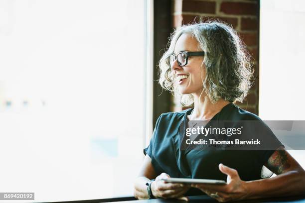 smiling businesswoman with digital tablet listening during meeting in office - wisdom woman stock pictures, royalty-free photos & images