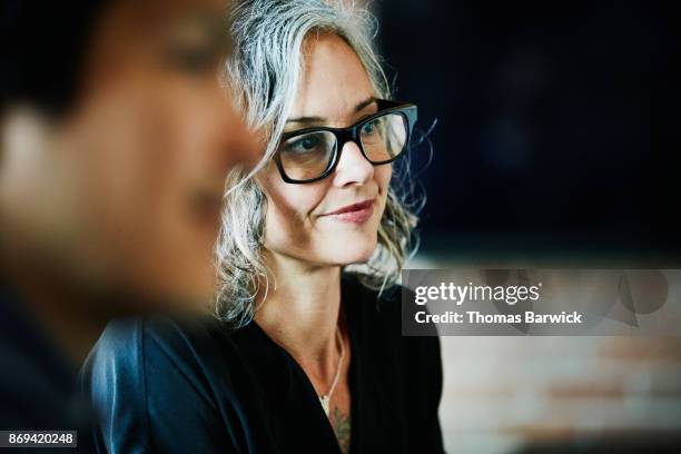 smiling businesswoman listening during team meeting in office conference room - business contemplation fotografías e imágenes de stock