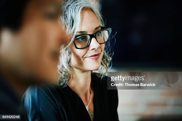 smiling businesswoman listening during team meeting in office conference room - honesty stock pictures, royalty-free photos & images