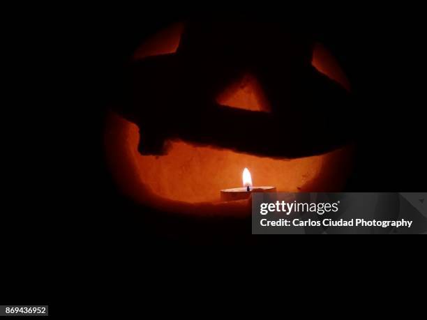 candle shining inside jack o lantern in the darkness - ugly pumpkins stock-fotos und bilder