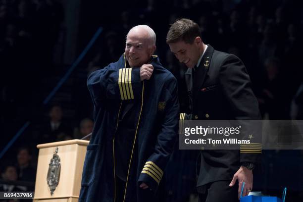 Sen. John McCain, R-Ariz., dons a Navy bath robe given to him by MIDN Brigade Commander Austin Harmel, right, during a ceremony where McCain and...