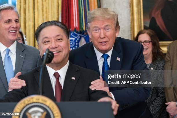 President Donald Trump jokes with Broadcom CEO Hock Tan as he announces that Broadcom woud be moving back to the US in the Oval Office at the White...