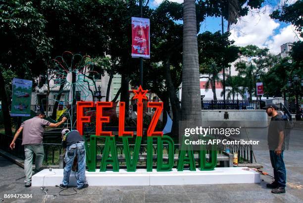 Men work on the installation of a christmas sign in Caracas on November 2, 2017. Venezuela will put into circulation a new bank note of 100,000...