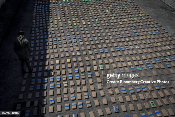 an anti-narcotics police officer stands guard over packages of cocaine - drug smuggling 個照片及圖片檔