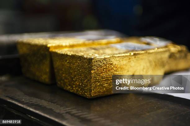 gold bullion bars sit following casting at a refinery - minero fotografías e imágenes de stock