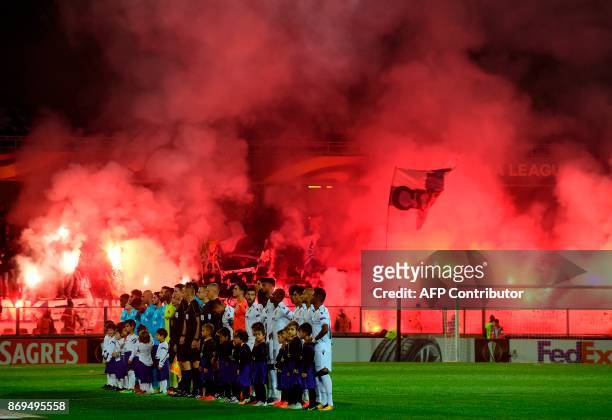 Marseille supporters light flares as players pose before the start of the UEFA Europa League group I football match Vitoria SC vs Marseille at the D....