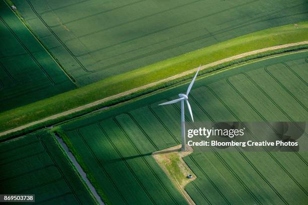 a wind turbine stands in a field of agricultural crops - clean energy fotografías e imágenes de stock