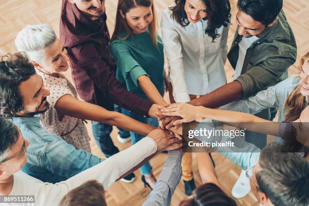 large group of people standing in circle and stacking hands - hand stack stock pictures, royalty-free photos & images