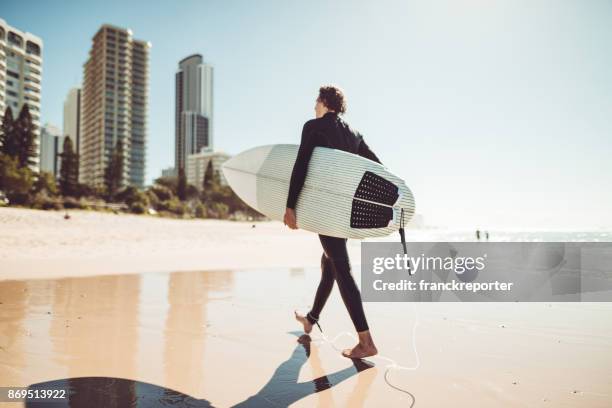 surfer walking in surfers paradise beach in australia - gold coast surfing stock pictures, royalty-free photos & images