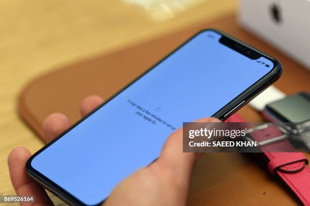 Customers setup an iPhone X at an Apple showroom in Sydney on November 3, 2017. - Apple iPhone X went for sale in Australia with long queues outside...