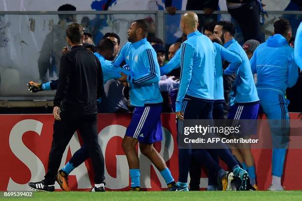 Teammates try to calm down Marseille's defender Patrice Evra as he tries to kick a supporter before the start of the UEFA Europa League group I...