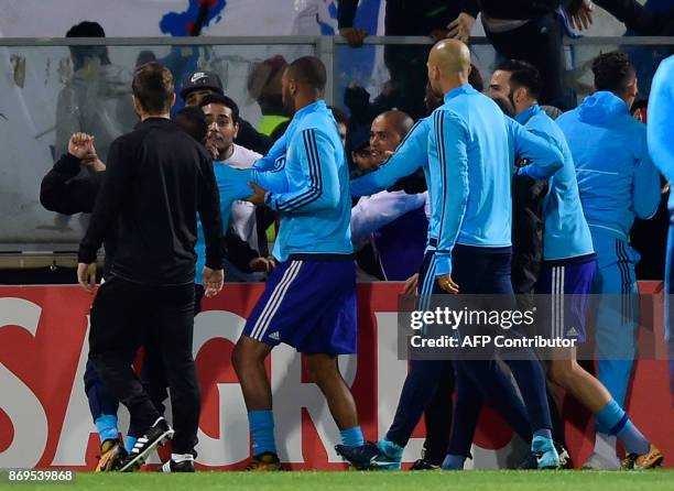 Teammates try to calm down Marseille's French defender Patrice Evra as he argues with supporters before the start of the UEFA Europa League group I...