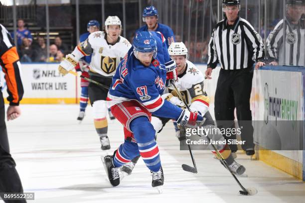Steven Kampfer of the New York Rangers skates with the puck against Oscar Lindberg of the Vegas Golden Knights at Madison Square Garden on October...