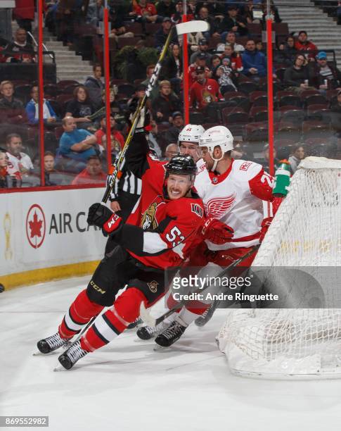 Jack Rodewald of the Ottawa Senators skates behind the net against Mike Green and Xavier Ouellet of the Detroit Red Wings at Canadian Tire Centre on...