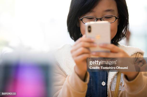 Girl tries an iPhone X at the Apple Omotesando store on November 3, 2017 in Tokyo, Japan. Apple launched the latest iPhone featuring face recognition...