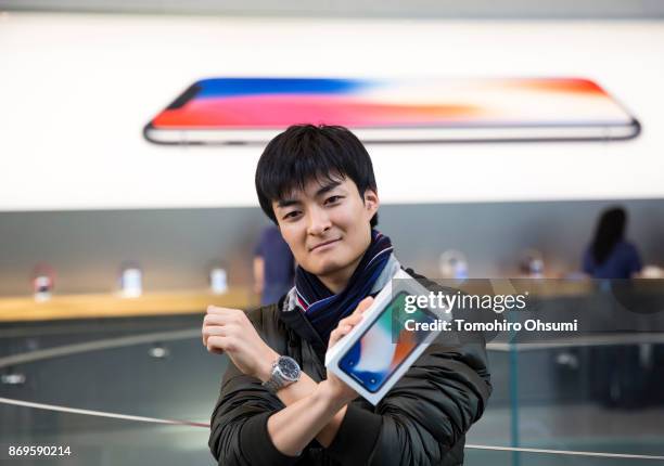 The first customer to the Apple Omotesando store holds a box containing his iPhone X as he poses to the media on November 3, 2017 in Tokyo, Japan....