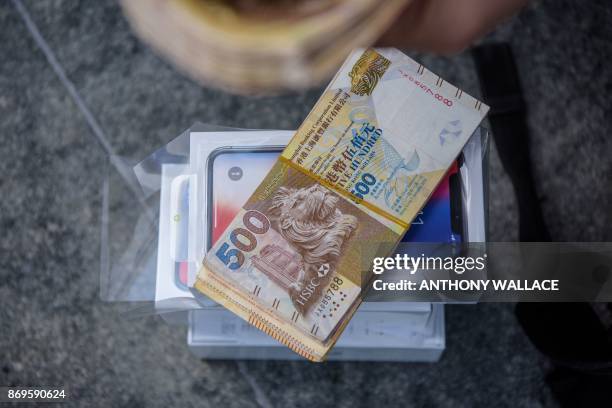 Cash belonging to a reseller is placed over a pile of iPhone X's near an Apple store in Hong Kong on November 3, 2017. - Apple profits soared by a...