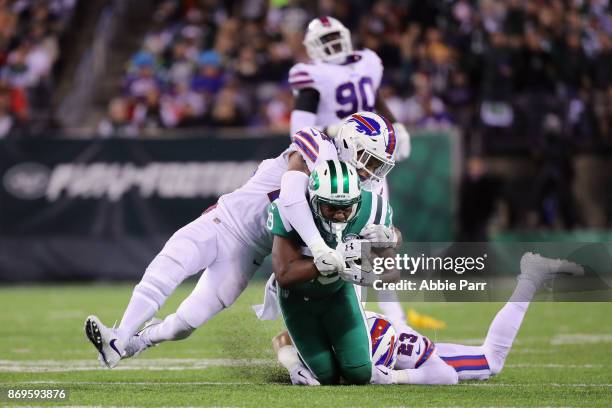 Bilal Powell of the New York Jets is taken down by Micah Hyde and Jordan Poyer of the Buffalo Bills during the third quarter of the game at MetLife...