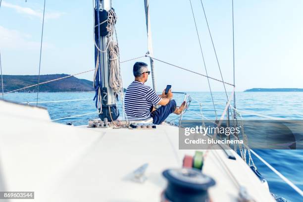 man op een luxejacht op zoek naar een smartphone - captain yacht stockfoto's en -beelden