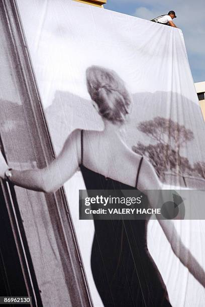 People set up the official poster of the Cannes' film festival 62nd edition on the Festivals' palace facade on May 11, 2009 in Cannes, south eastern...