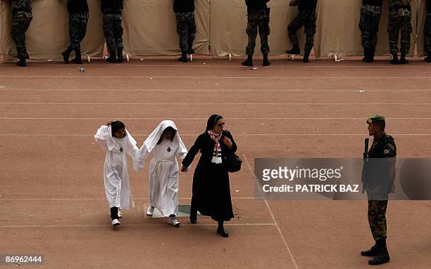 Christian nun hold hands with two Jordanian Christian girls as she walks past a Jordanian soldier standing guard at Amman's stadium where Pope...