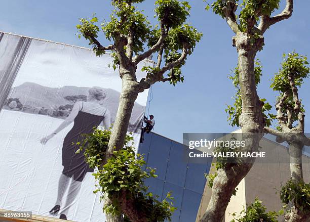 People set up the official poster of the Cannes' film festival 62nd edition on the Festivals' palace facade on May 11, 2009 in Cannes, south eastern...