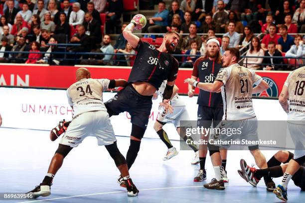 Luka Karabatic of Paris Saint Germain is trying to shoot the ball against Wilson Davyes and Mickael Grocaut of Dunkerque Handball during the Lidl...