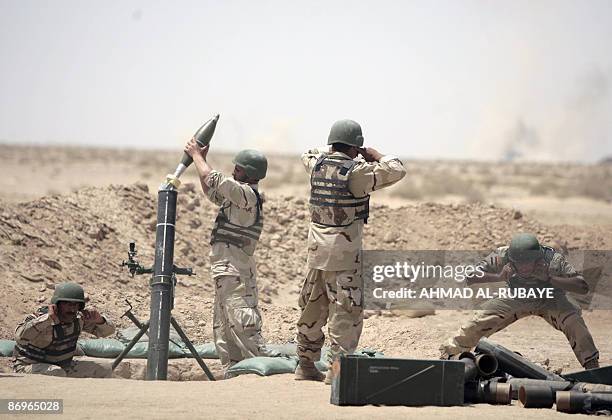 Iraqi soldiers block their ears as a 120mm mortar shell is loaded during a training operation at a desert range some 40 kms south of the town of...