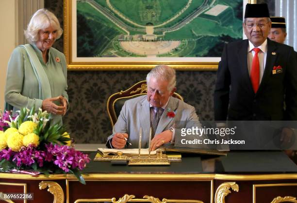 Prince Charles, Prince of Wales signs the visitors book as Camilla, Duchess of Cornwall looks on ahead of Tea with His Majesty The Yang di-Pertuan...