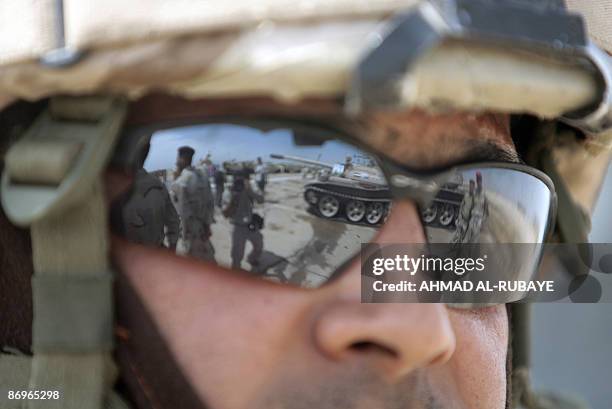 Reflected in the sun glasses of a foreign soldier, Iraqi soldier walk past Russian made tanks during training operations at a desert range some 40...
