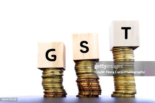 gst word on wood block on top of coins stack - gst stock-fotos und bilder