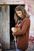 Caucasian young woman with blond hair holds a hen in a farm