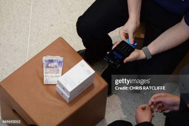 Customer pays for his Apple iPhone X after being one of the first to purchase the newly released smartphone at Apple's Regent Street store in central...