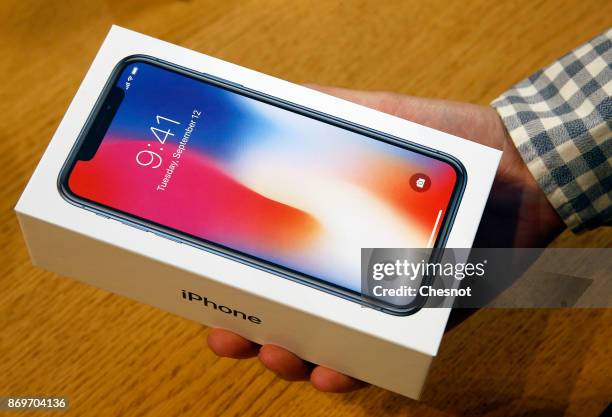 Customer holds a box containing an Apple iPhone X, the new model of Apple smartphone at the Apple Store Saint-Germain on November 3, 2017 in Paris,...