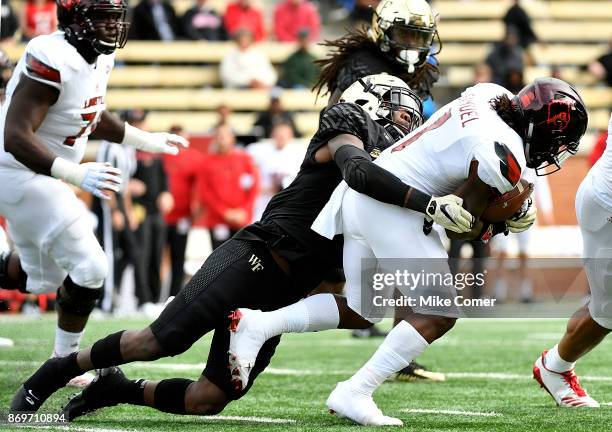 Defensive back Cameron Glenn of the Wake Forest Demon Deacons tackles wide receiver Traveon Samuel of the Louisville Cardinals during the football...