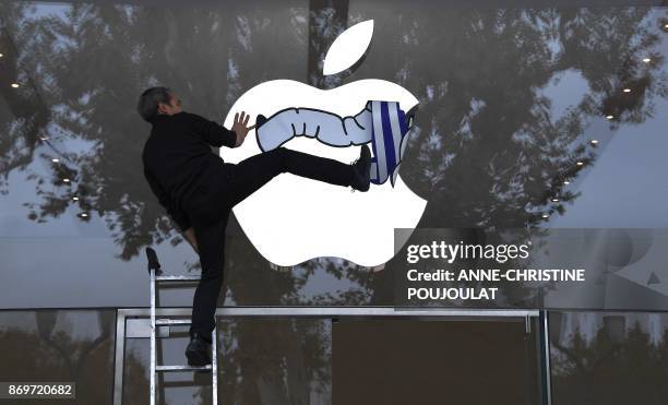 An activist from the Association for the Taxation of financial Transactions and Citizen's Action sticks a poster on the window of the Apple store...